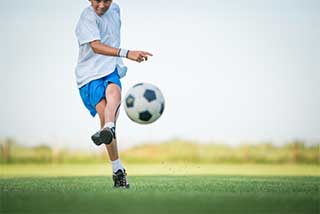 Teen boy kicking soccer ball