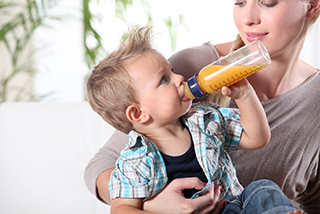 Mom helping toddler drink for a bottle